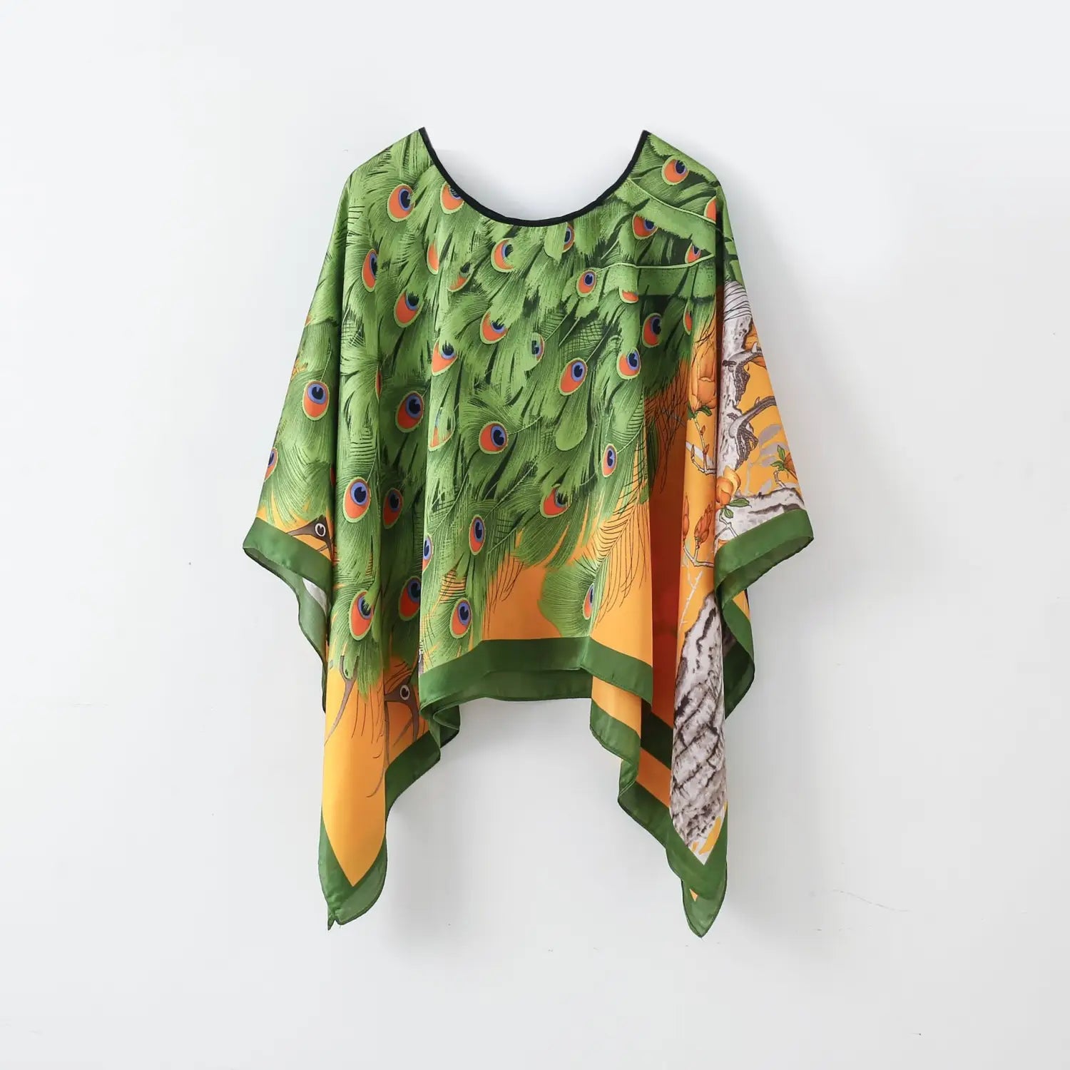 a flowing green and orange peacock feather print silk pullover shawl cape outerwear with black trim shown from the back side