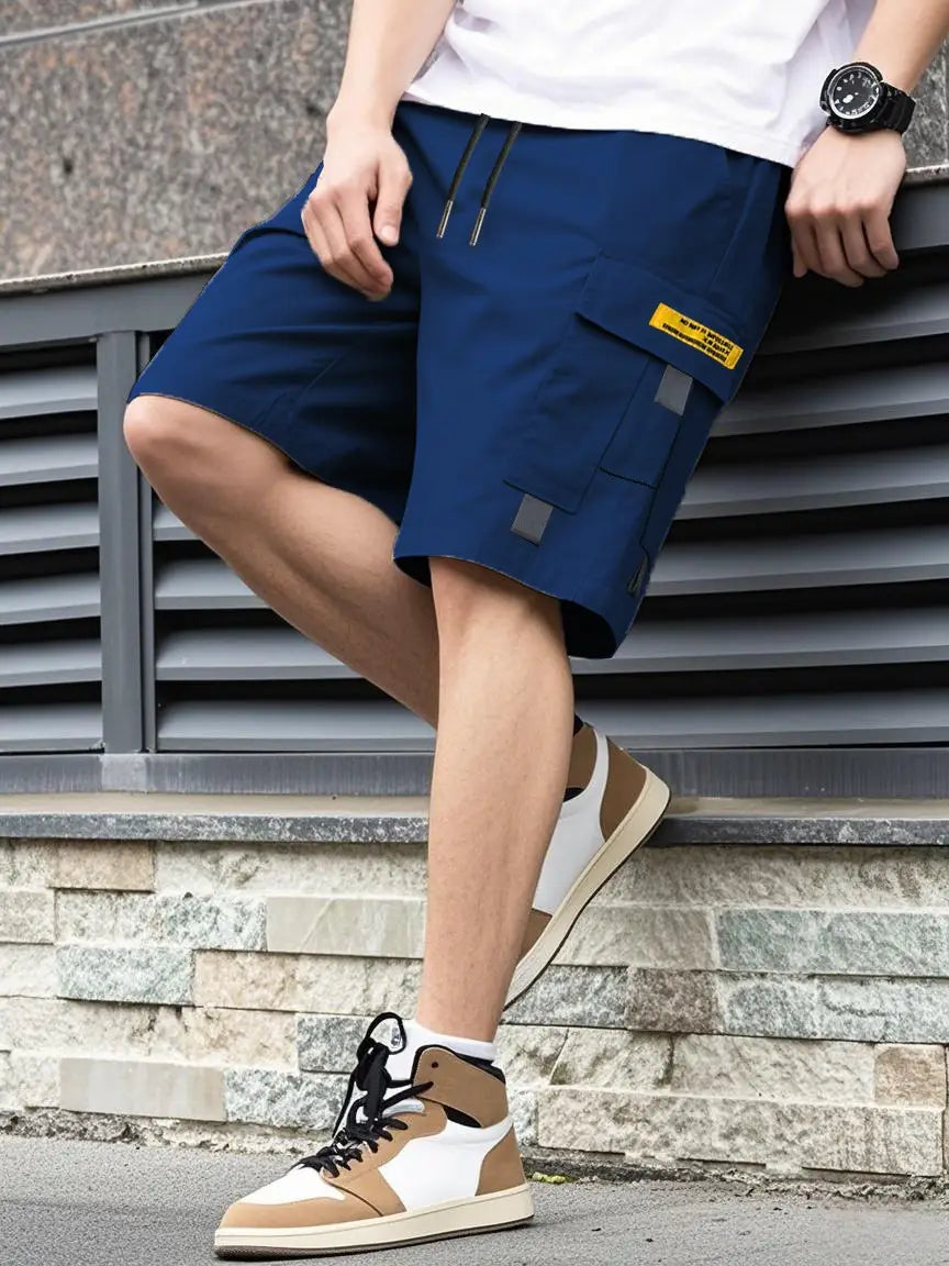Shorts cargo utilitaires pour homme en bleu marine, avec des accents jaunes et gris, offrant un cordon de serrage décontracté pour l’été et plusieurs poches.