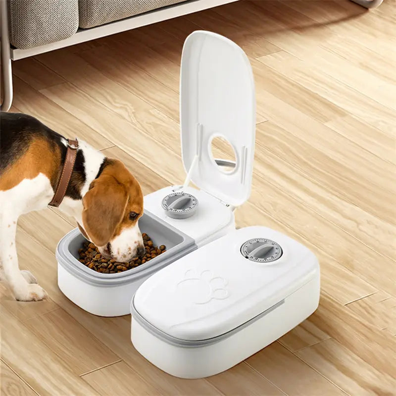 White and gray dual-compartment automatic pet feeder with a paw print design on the lid for gravity feeding and food dispensing.