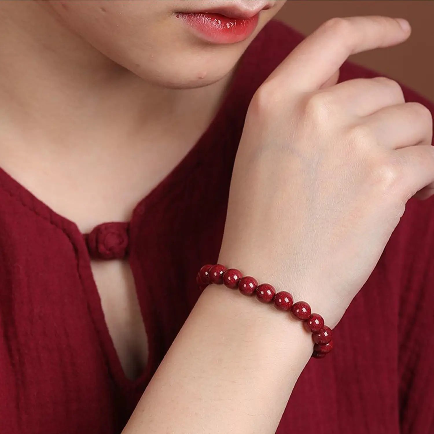 A polished red cinnabar spherical bead bracelet featuring smooth deep red beads worn on a wrist.