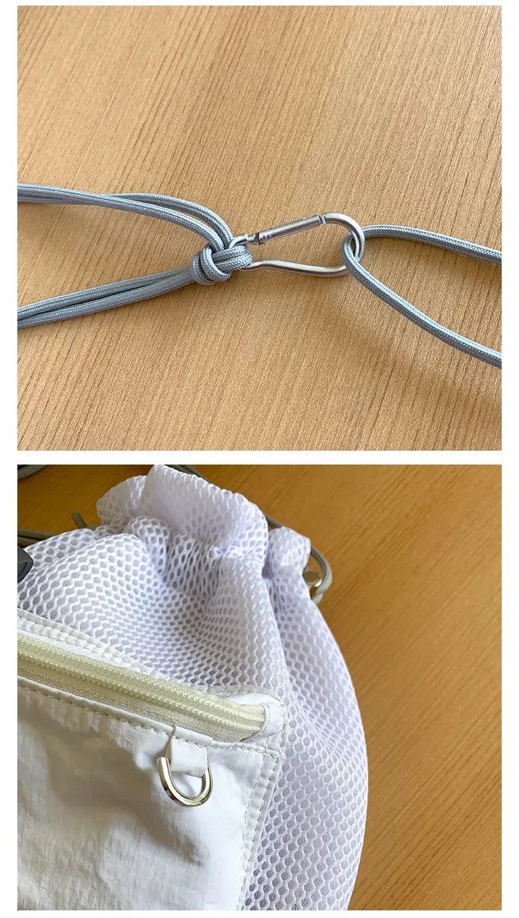 White mesh drawstring bucket bag with a zipper pocket, metal hardware, and a mini pink heart charm accessory