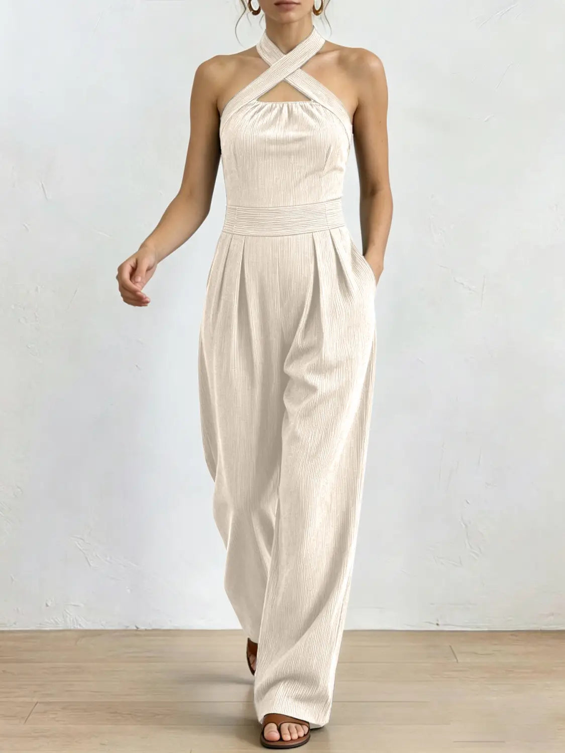 Ein elfenbeinfarbener gerippter Halterneck-Jumpsuit mit gekreuztem Ausschnitt und Hosen im weitem Bein.