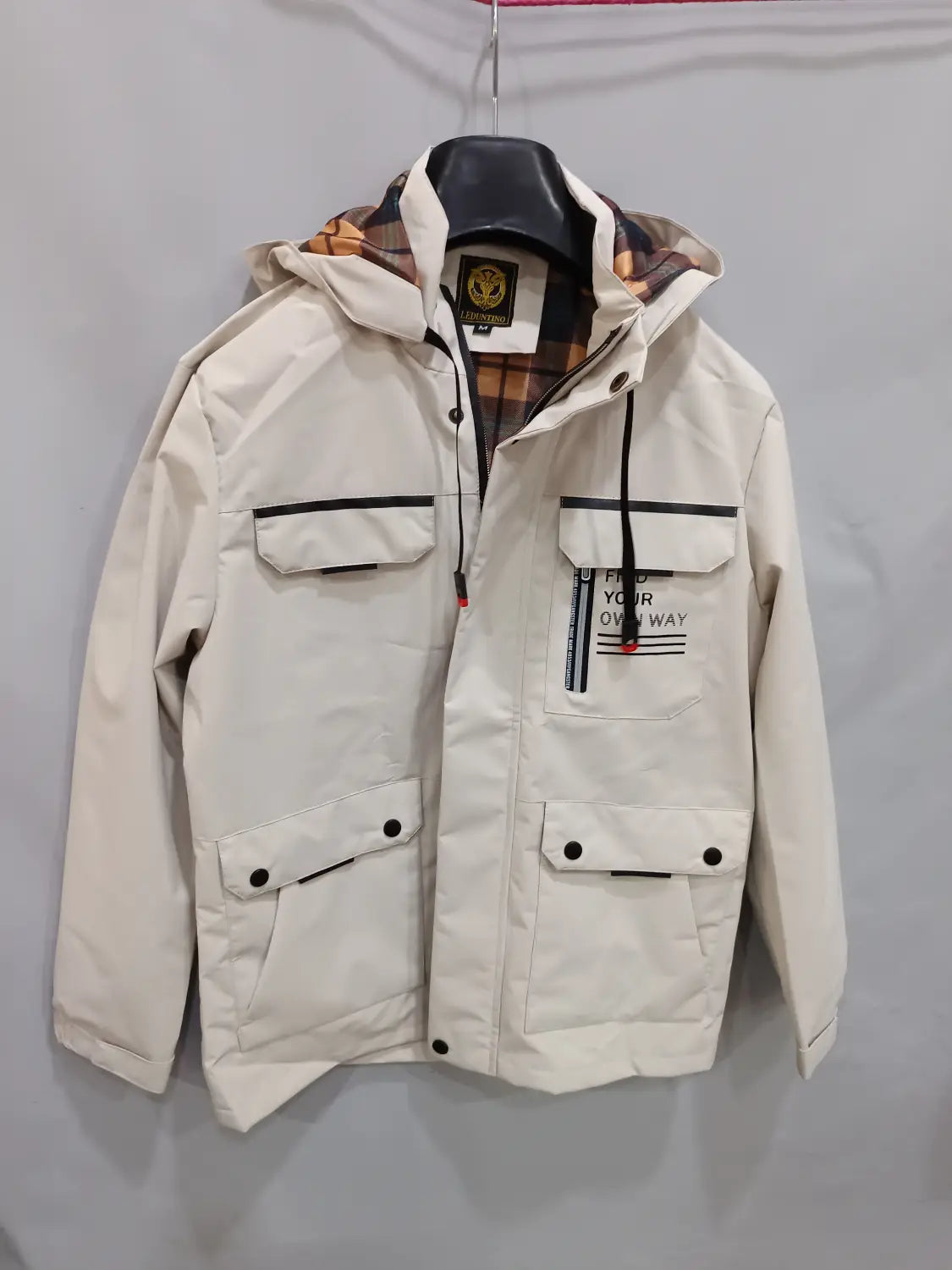 Men winter hooded parka coat in beige with black trim featuring a plaid-lined interior and front pockets with find your own way graphic.