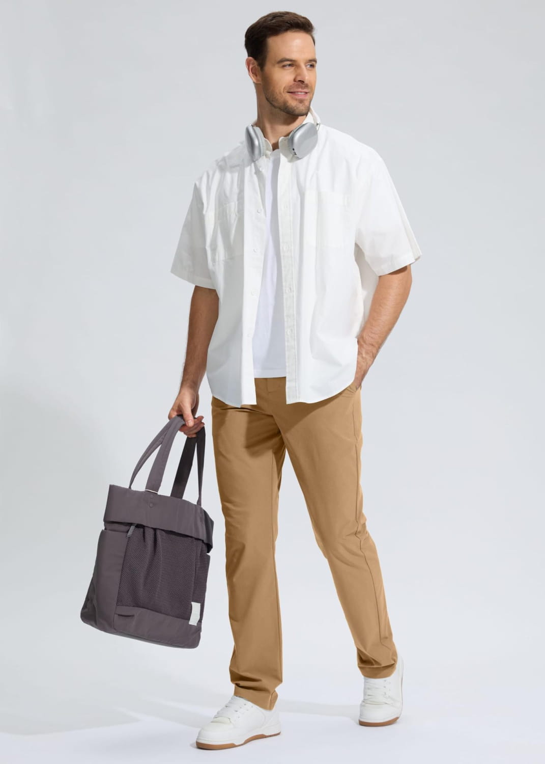 Gray canvas tote bag with black straps and a front pocket paired with quick drying casual stretch pants.