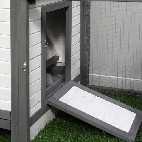 Rampe en bois gris et blanc menant à un poulailler en bois avec boîte de ponte, enclos pour animaux.