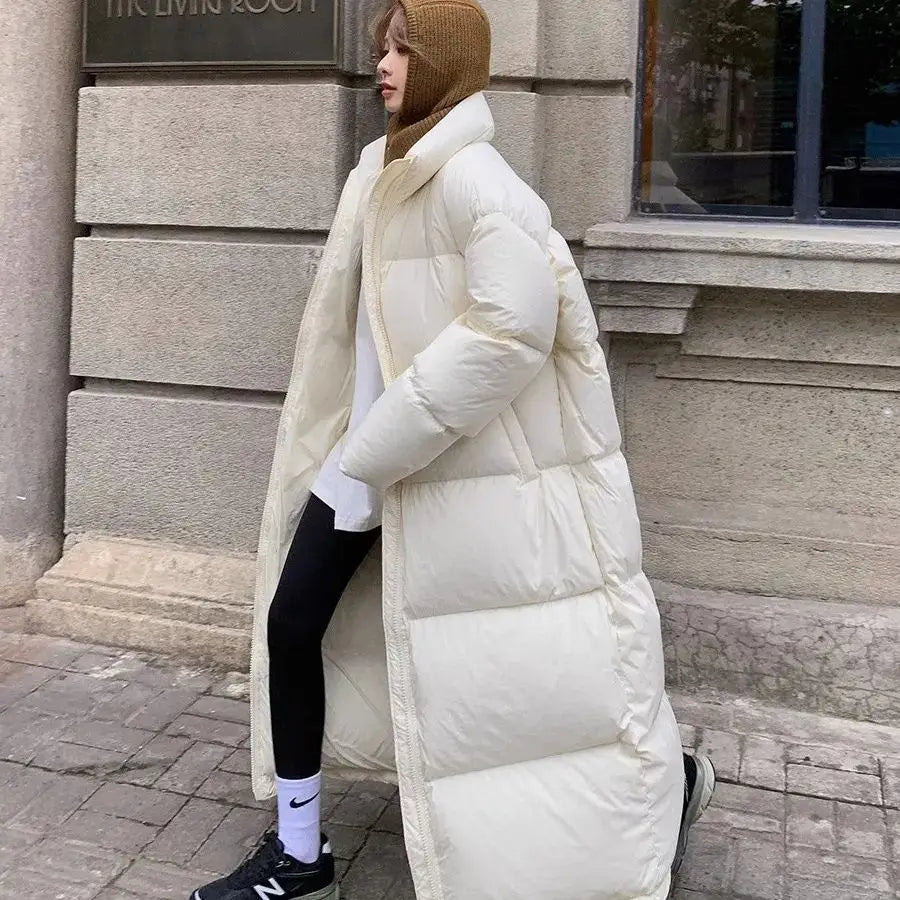 Cream-colored quilted down coat with a high collar and long sleeves designed for women as a long cotton winter jacket.