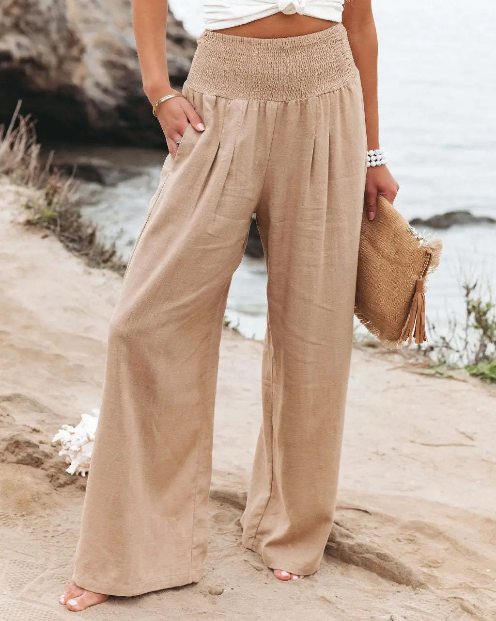 Beige smocked wide leg pants for women featuring a high waist and textured elastic waistband in solid color.
