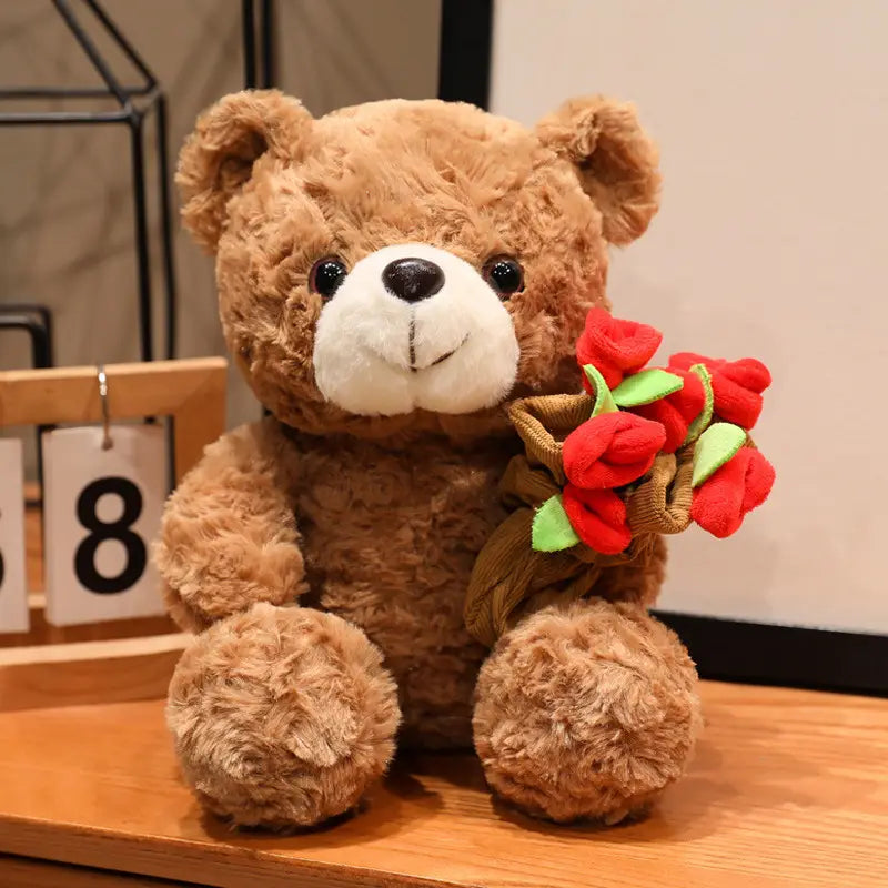 Ein brauner Plüsch-Teddybär mit weißer Schnauze und schwarzen Knopfaugen hält einen Strauß aus roten Stoffrosen in einem geflochtenen Korb; geeignet als Valentinsgeschenk, Größe 16–25 cm.