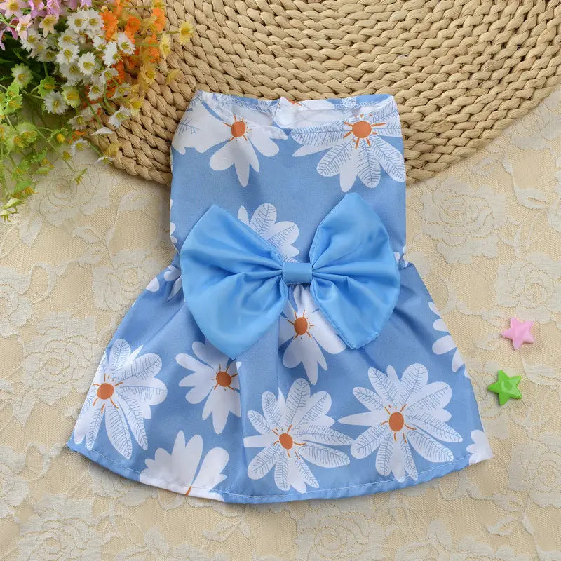 Light blue floral dog princess dress with white daisy print and a matching large bow at the waist designed for pet apparel.
