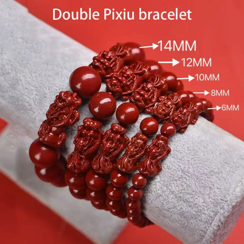 Hand carved purple gold cinnabar double pixiu bracelet featuring red intricately carved figurines and smooth round beads in varying sizes.