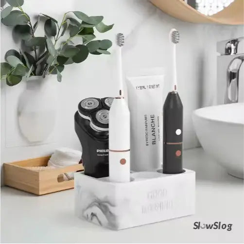 Ceramic toothpaste holder marble bathroom organizer with white marble texture rectangular design holding two electric toothbrushes and a black Philips shaver.