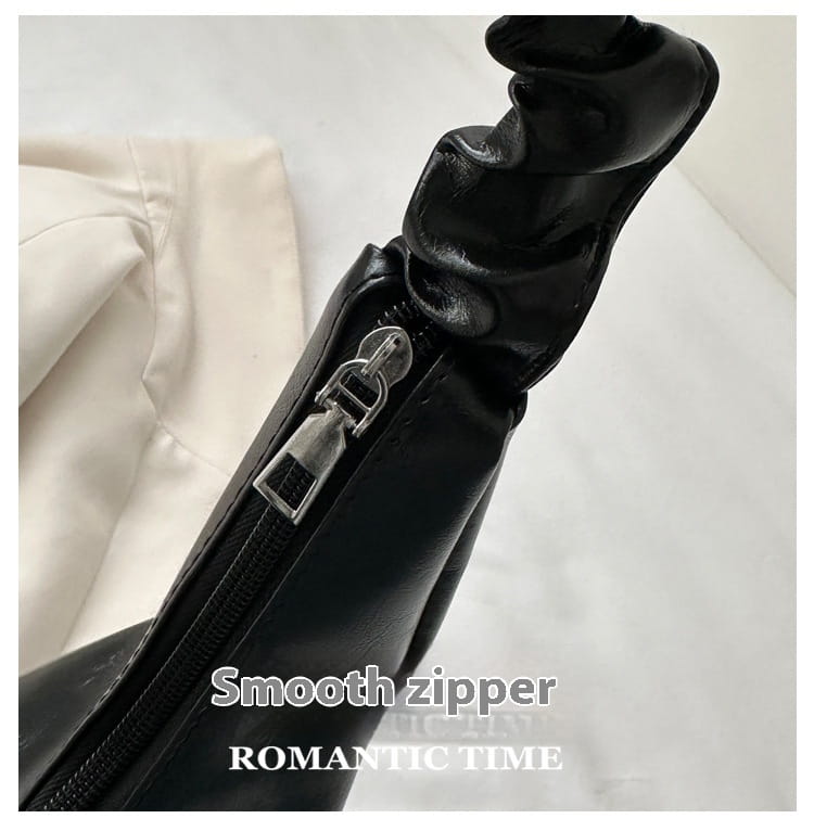 Black leather ruched shoulder bag featuring smooth zipper detailing in a patent leather handbag design.