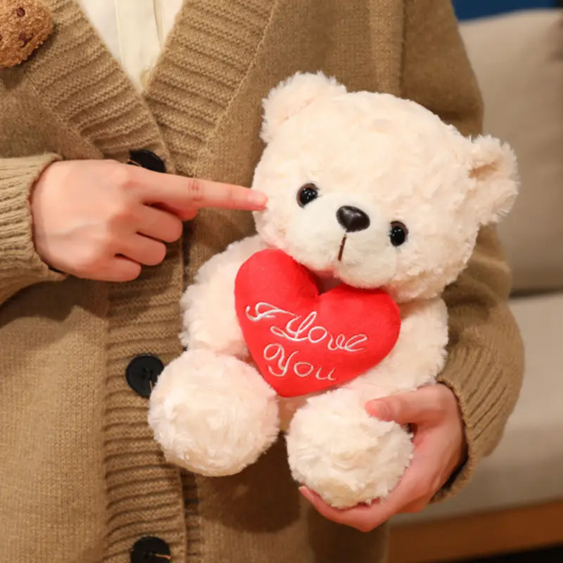 Ein weicher weißer Plüsch-Teddybär hält ein rotes Herz mit dem Text „I love you“; präsentiert als Teddybär-Plüschtier mit Rosen, Valentinsgeschenk, 16–25 cm.