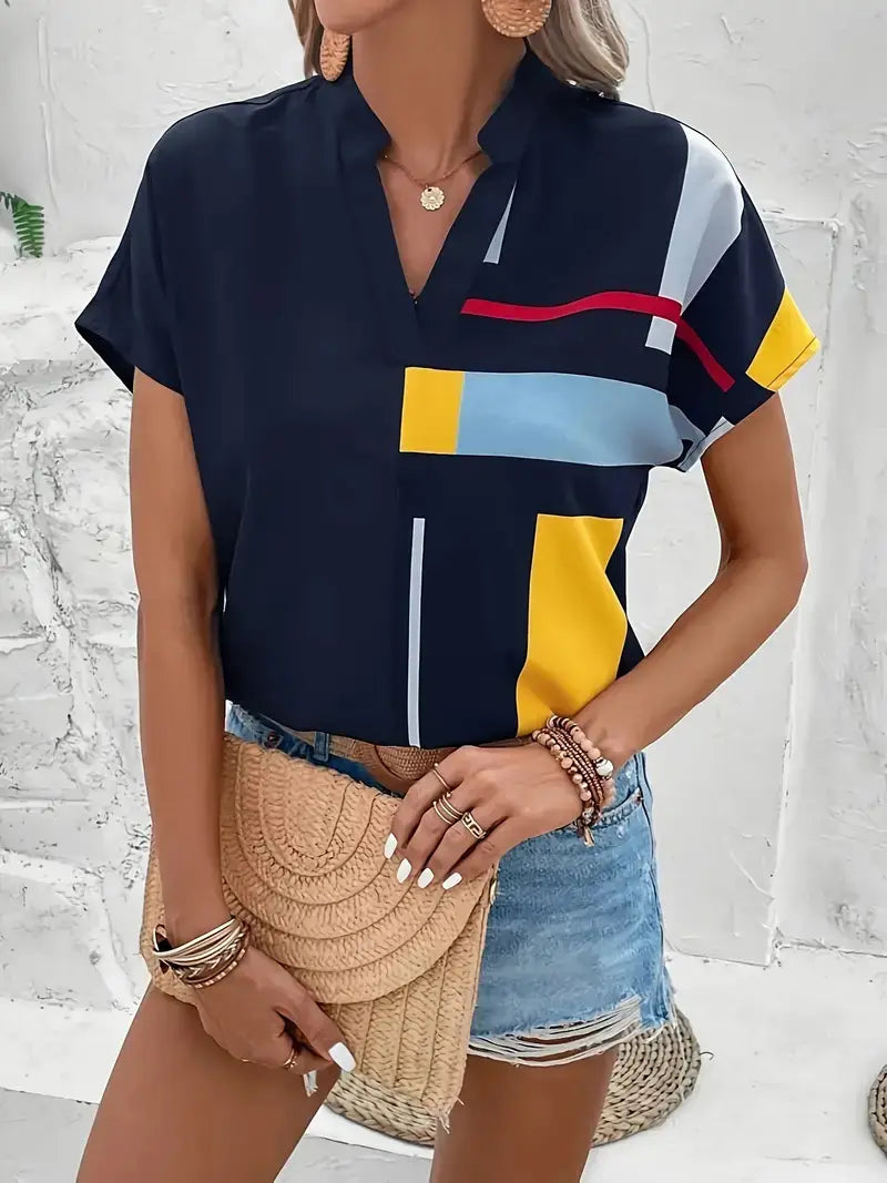 Navy blue short-sleeved abstract print V-neck blouse with bold yellow light blue and red geometric panels made of stretch satin fabric.
