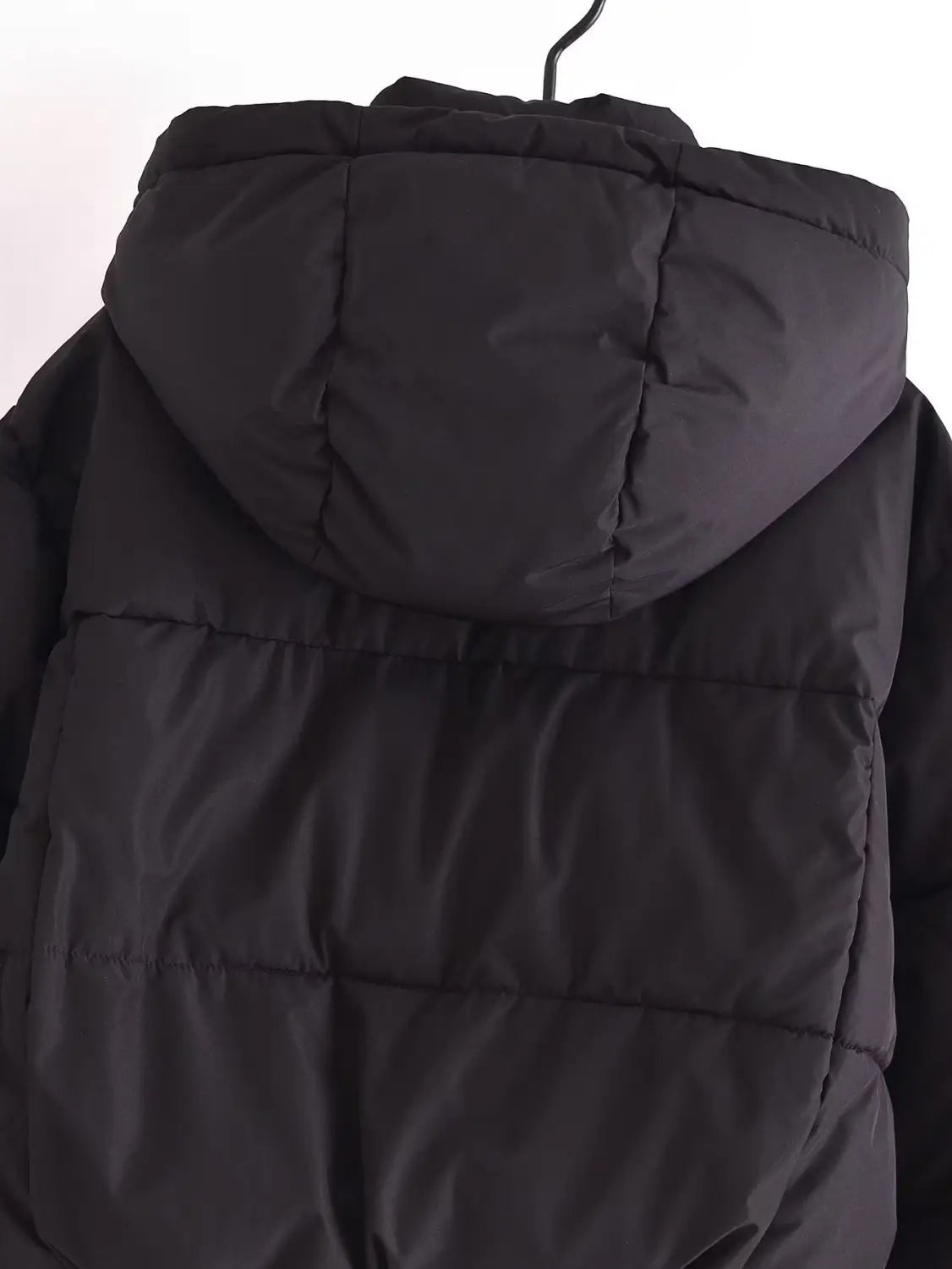 Black quilted puffer coat with a hood made of insulated material for cold weather protection.
