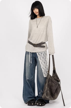 Sac bandoulière en cuir texturé marron foncé à la silhouette souple, avec des détails de couture visibles, assorti à un jean noir à jambes larges en patchwork de dentelle en forme d’étoiles.