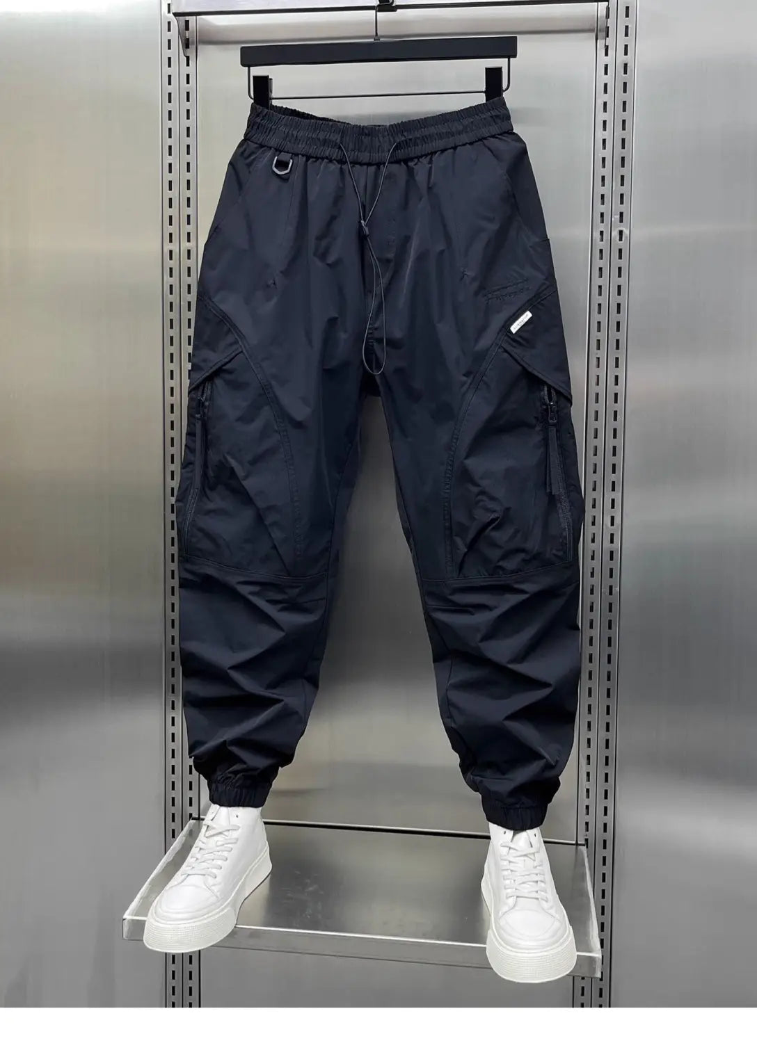 Men’s tapered black cargo joggers with elastic drawstring waist, multiple pockets, elastic cuffs, and lightweight nylon material.