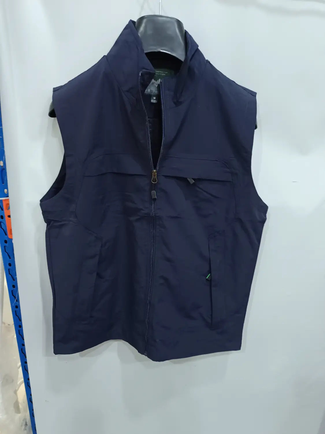 Chaleco utilitario impermeable sin mangas de color azul marino oscuro con cremallera de longitud completa y múltiples bolsillos.
