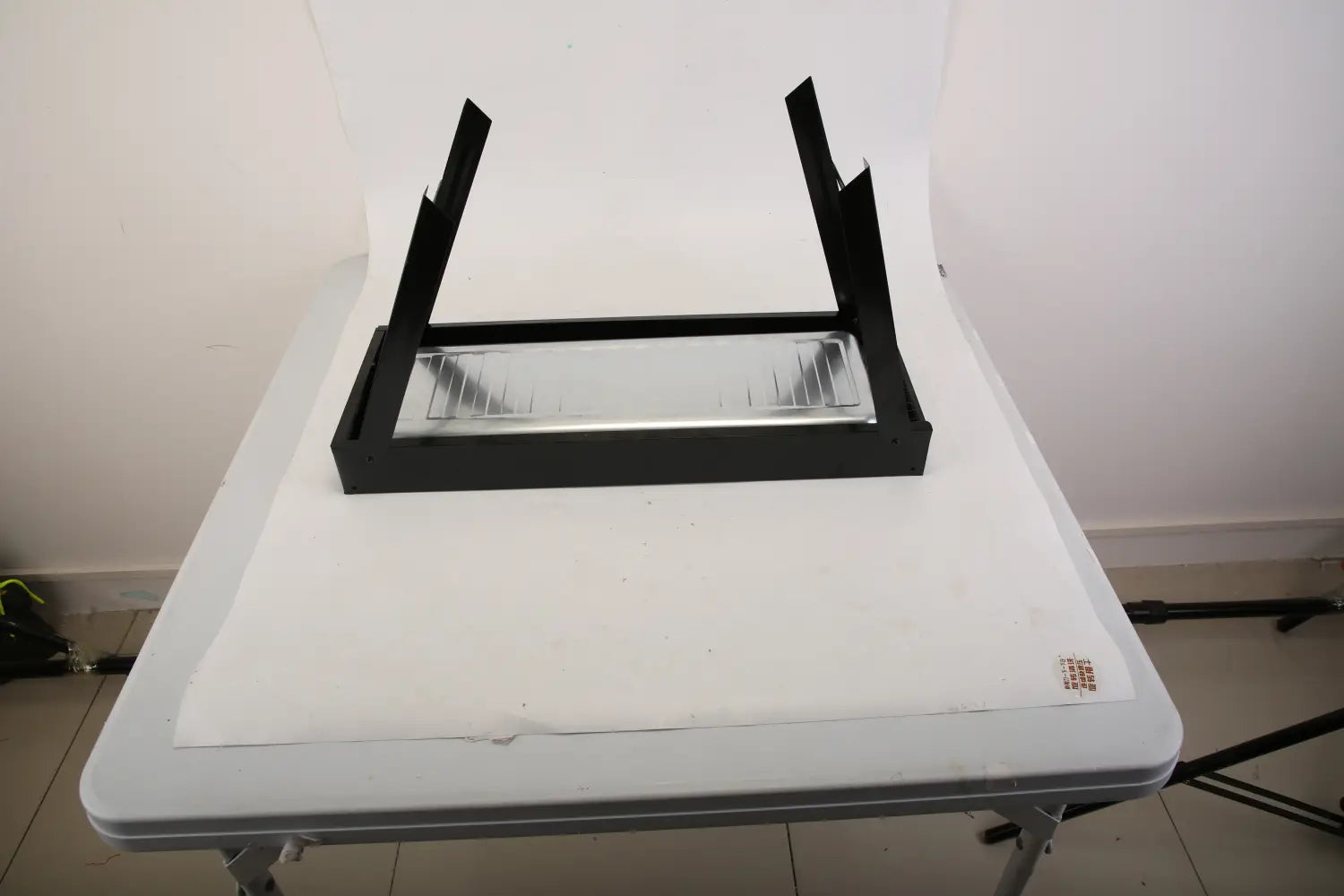 Black rectangular portable charcoal BBQ grill with a transparent glass insert and foldable stainless steel grid pattern.