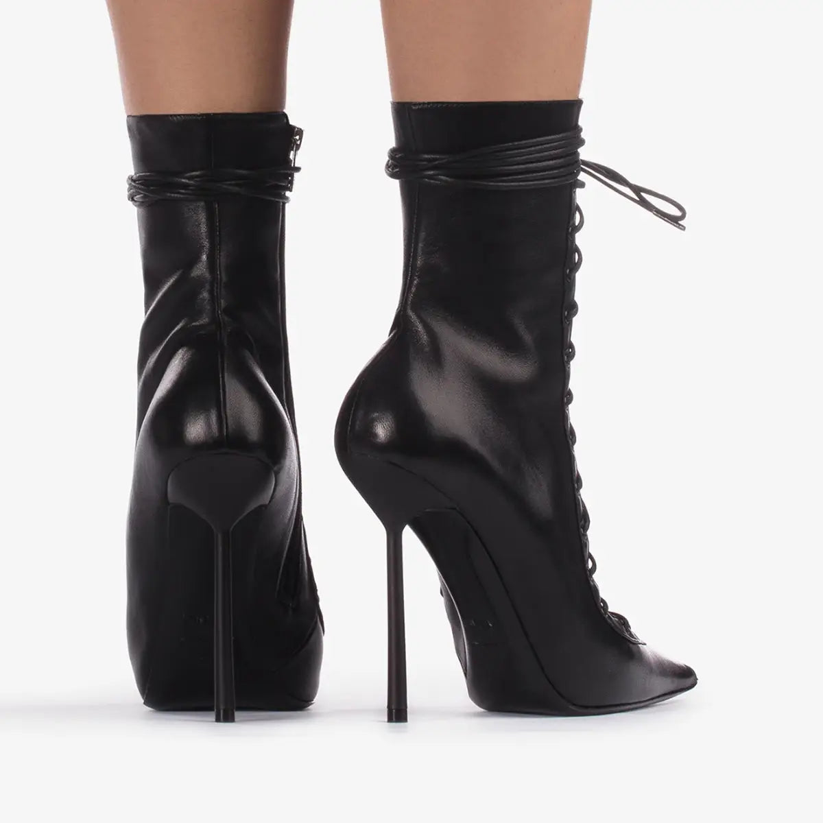 Des bottines en cuir noir, à la finition brillante élégante et à des talons aiguilles hauts, rappelant des sandales à talon aiguille haut à bout pointu en mesh à lacets.