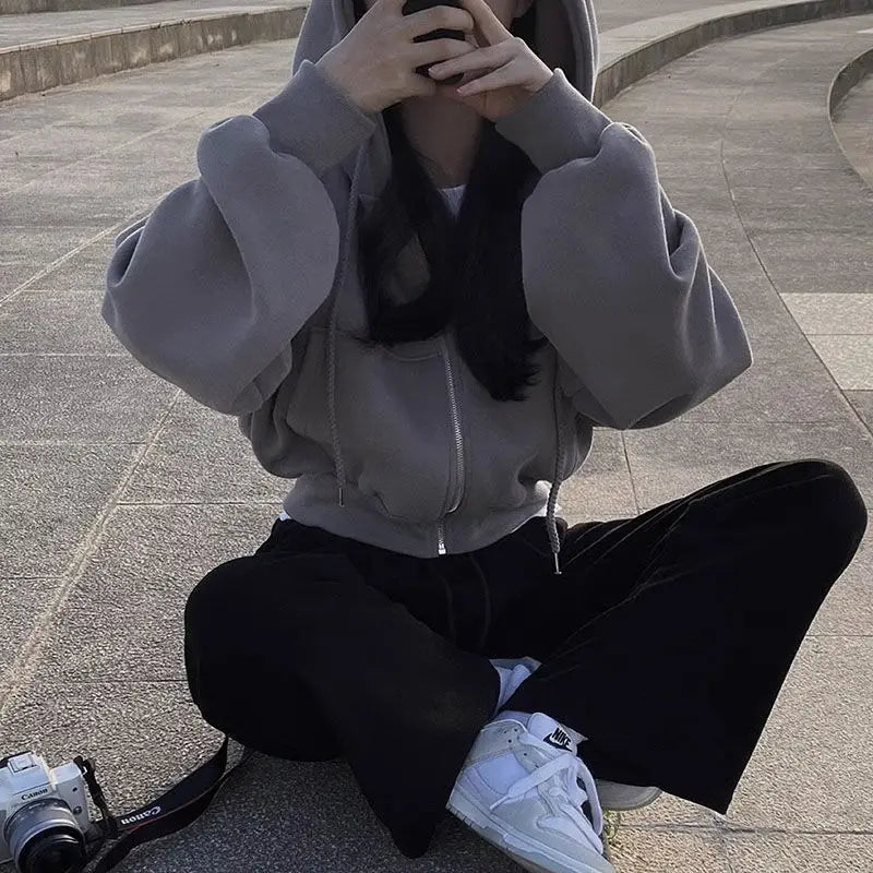 Grauer Hoodie mit Kapuze, vorderem Reißverschluss und Kordeln, die das Design des dunkelblauen Samt-Velours, wattierten Kapuzenpullovers mit schmaler Passform ergänzen.