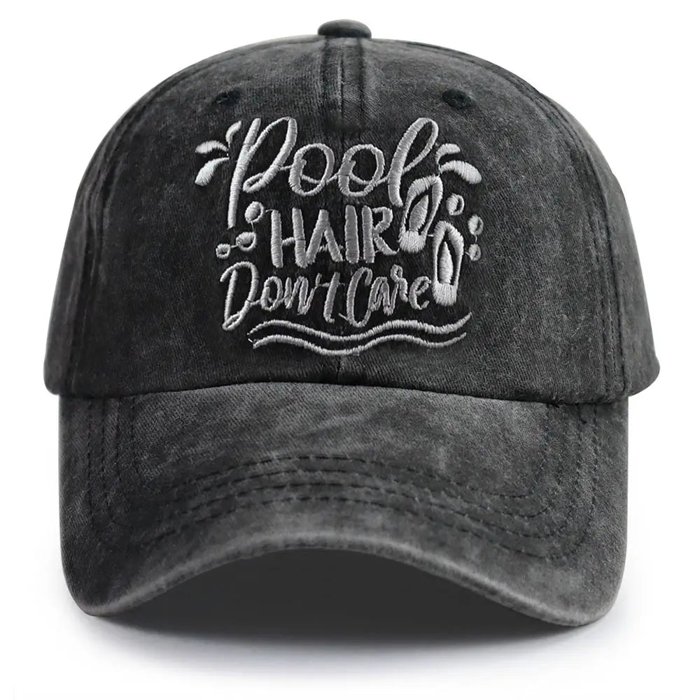 A dark gray distressed cotton baseball cap with embroidered white text reading pool hair don’t care and decorative wave and footprints is featured in the pool hair don’t care vintage baseball cap product.