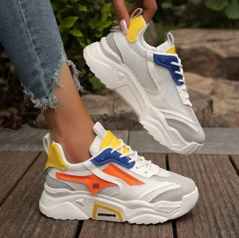 Womens mesh platform sneakers featuring breathable chunky shoes in white and gray with vibrant yellow, blue, and orange accents on the sides and heel.