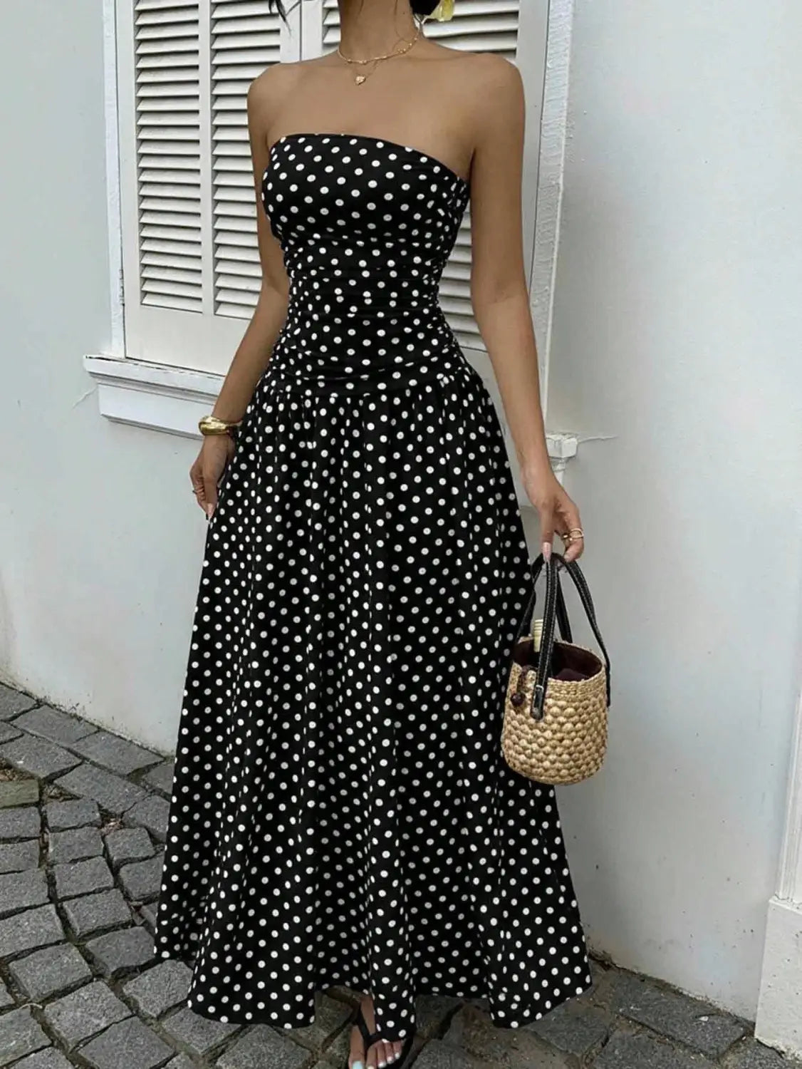 black strapless maxi dress in fabric with white polka dots featuring an off shoulder design.