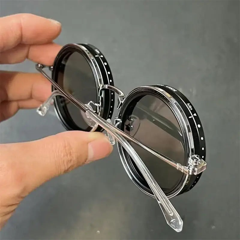 Lunettes de soleil rondes unisexes résistantes aux UV, avec lentilles à monture noire, branches transparentes et design de monture métallique au style inspiré du vintage.