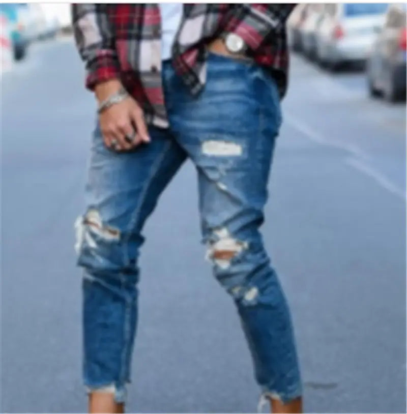 Men’s distressed blue denim ripped knee jeans featuring torn knees and frayed cuffs.