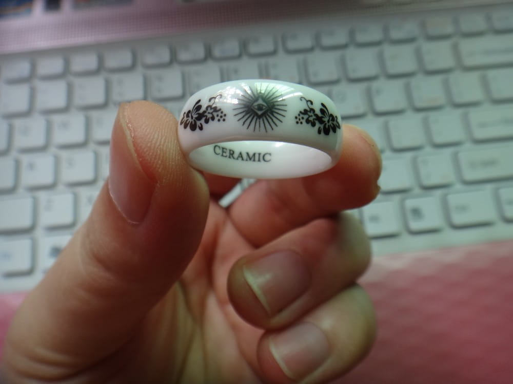 white ceramic ring with black floral and sunburst designs paired with black tungsten wedding ring featuring green aluminum 8mm band.