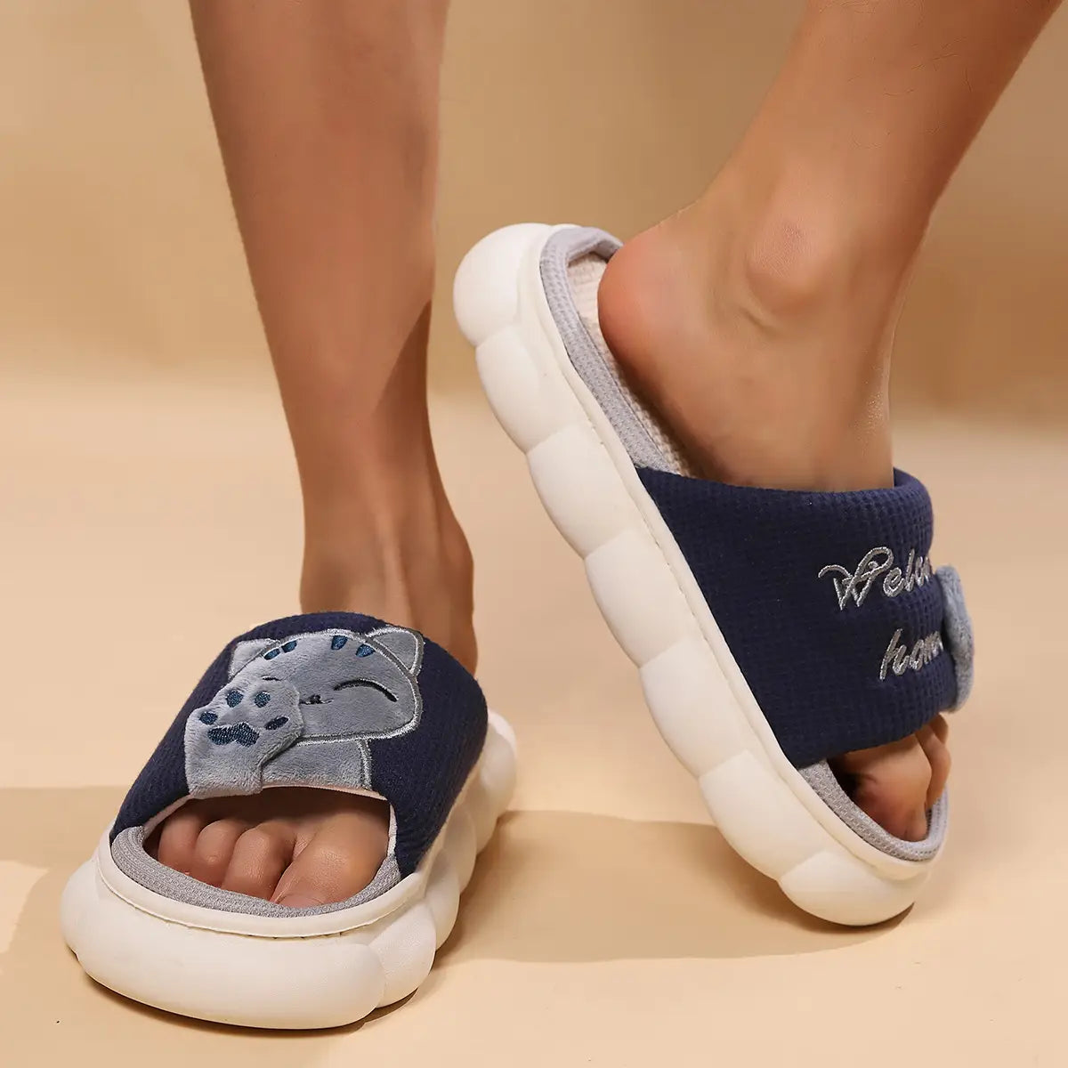 Navy blue and white plush unisex anti slip slide slippers with a gray embroidered cat face on the front.