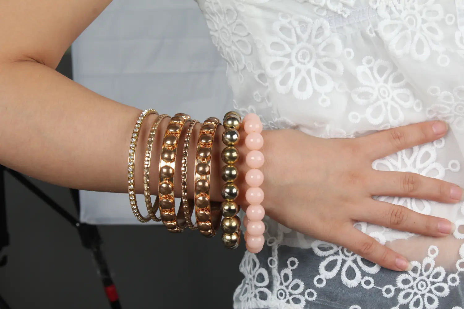 A stack of retro gold and pink rhinestone bangle bracelets made of gold-toned metal and pink beads worn on a wrist.