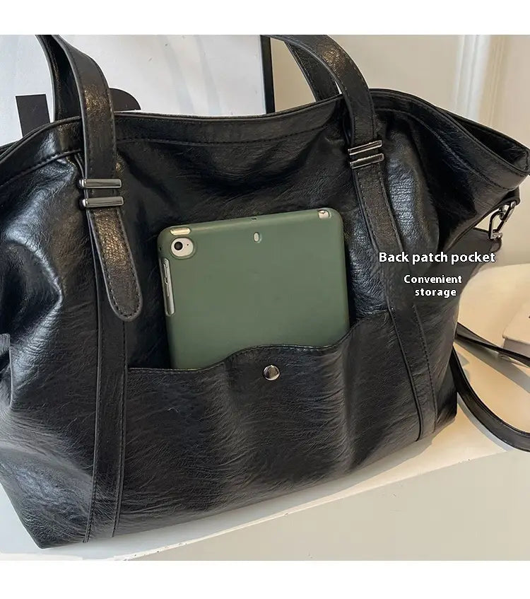 black faux leather tote bag with silver toned hardware and a back patch pocket shown from the back, complementing the brown leather star studded retro messenger bag collection.