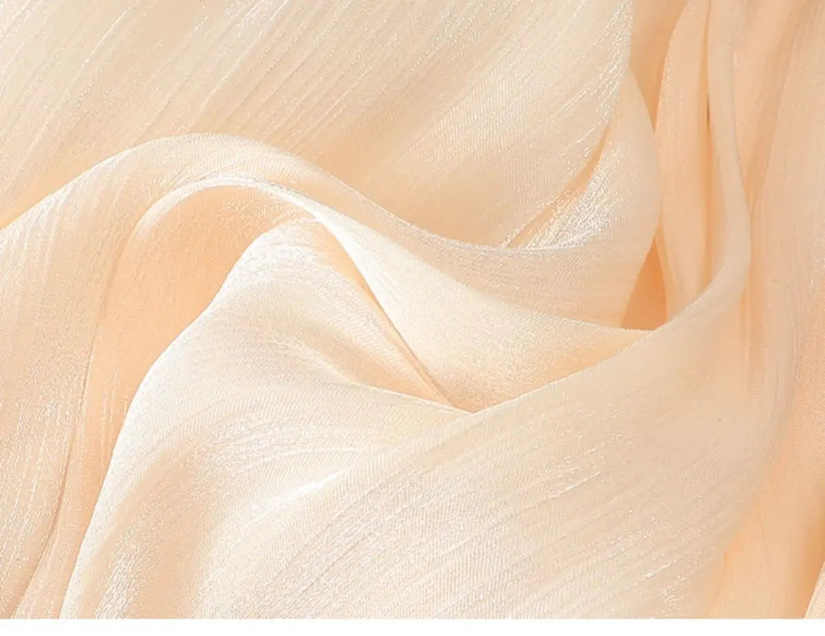 Ein zartes pfirsichfarbenes Chiffontuch mit dezentem Schimmer und weich fließenden Falten, das den irrisierenden Chiffon-Faltenrock ergänzt.