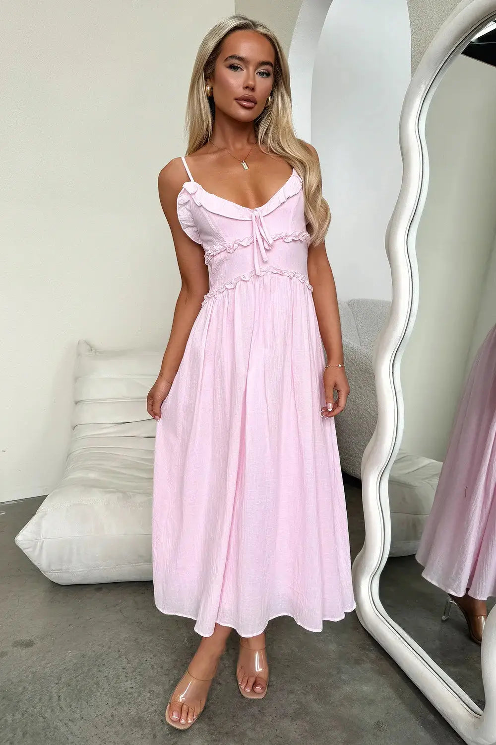 A soft pink flowing maxi vacation dress with delicate ruffled sleeveless straps and a gathered waistline.