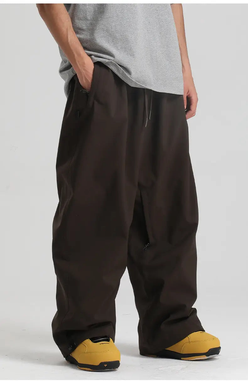 Dark brown waterproof windproof snow pants made of loose-fitting material with a drawstring waist and subtle side pockets suitable for work and outdoor activities.