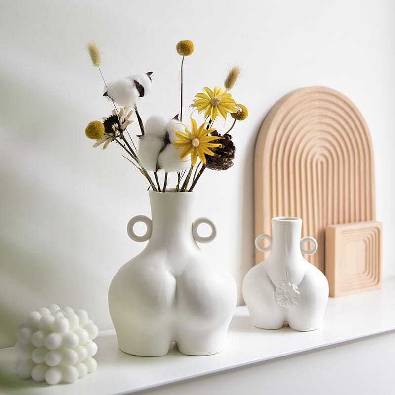 White ceramic female body ceramic vase with buttocks design and two circular handles on either side viewed from the back.