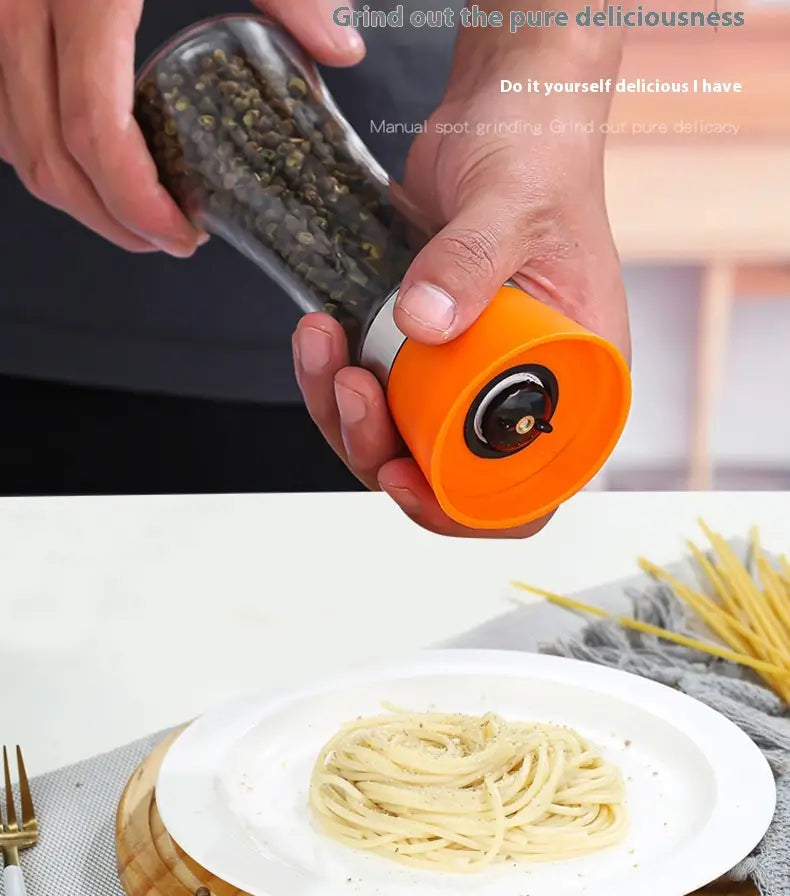 Moulin à poivre en verre transparent avec une base orange vif et des accents argentés, rempli de grains de poivre noirs, provenant d’un ensemble de moulin à poivre en acier inoxydable et en verre, pack de 4.
