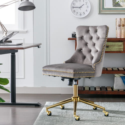 Chaise de bureau en velours capitonné gris avec piètement pivotant en métal à finition ton sur ton or et garniture à clous décoratifs.