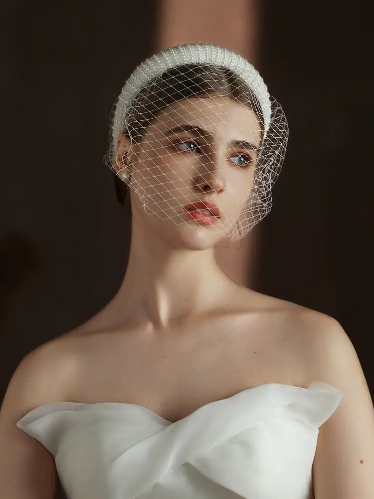A delicate white beaded vintage French Hepburn bridal veil headband featuring a fine mesh veil.