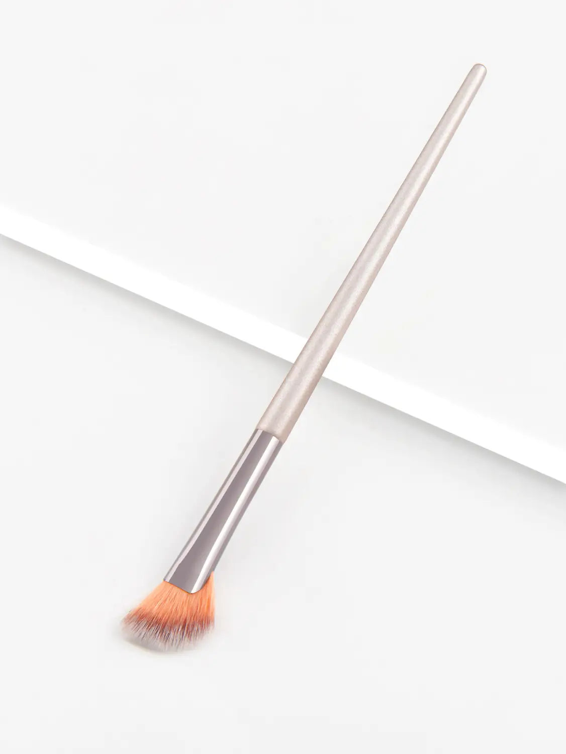 A sleek metallic-finish Finger Belly Makeup Brush professional contour tool with a tapered handle and soft orange-tipped bristles.