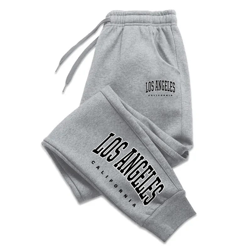 Pantalons de survêtement gris pour un usage sportif, fabriqués dans une matière souple, avec « Los Angeles, Californie » imprimé en lettres noires arquées sur la jambe et la ceinture.