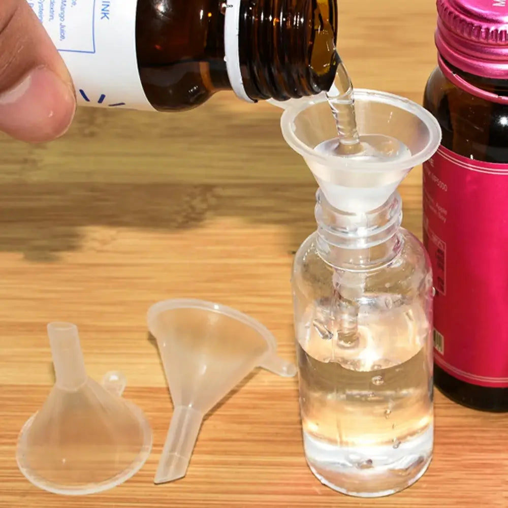 clear plastic funnel from the essential oil dispenser tool set 3pcs mini funnels being used to pour liquid from a brown bottle into a transparent glass bottle