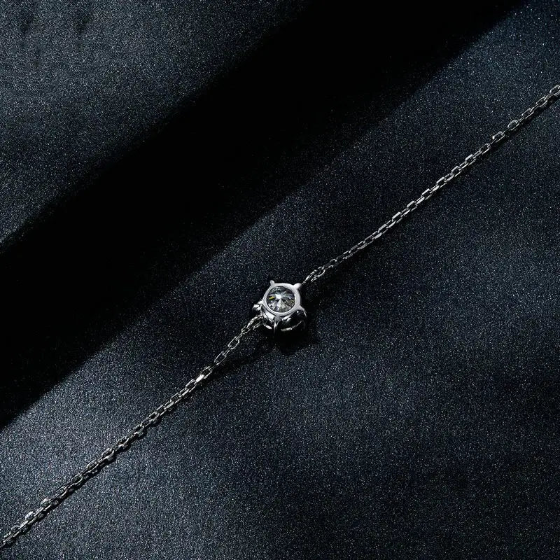 A delicate silver chain bracelet featuring a central solitaire moissanite diamond set in an elegant four-pronged bezel.