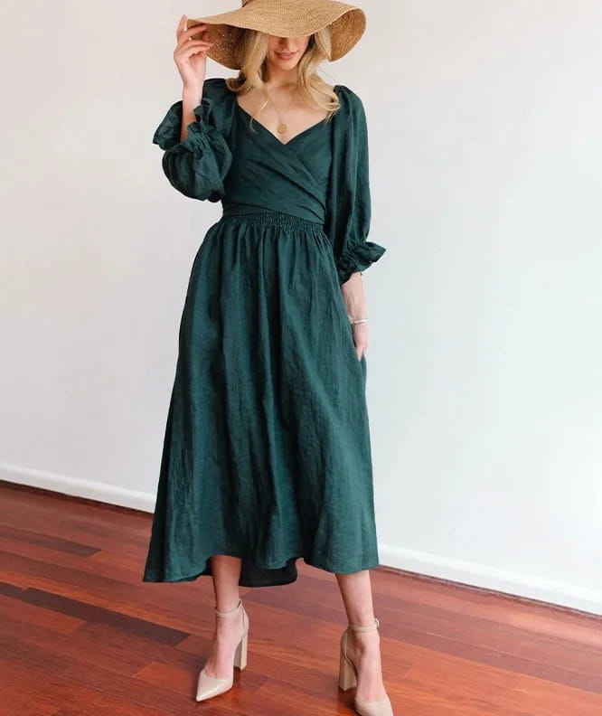 a deep emerald green v-neck lantern sleeve reversible midi dress with puffed sleeves and a fitted waist in flowing fabric