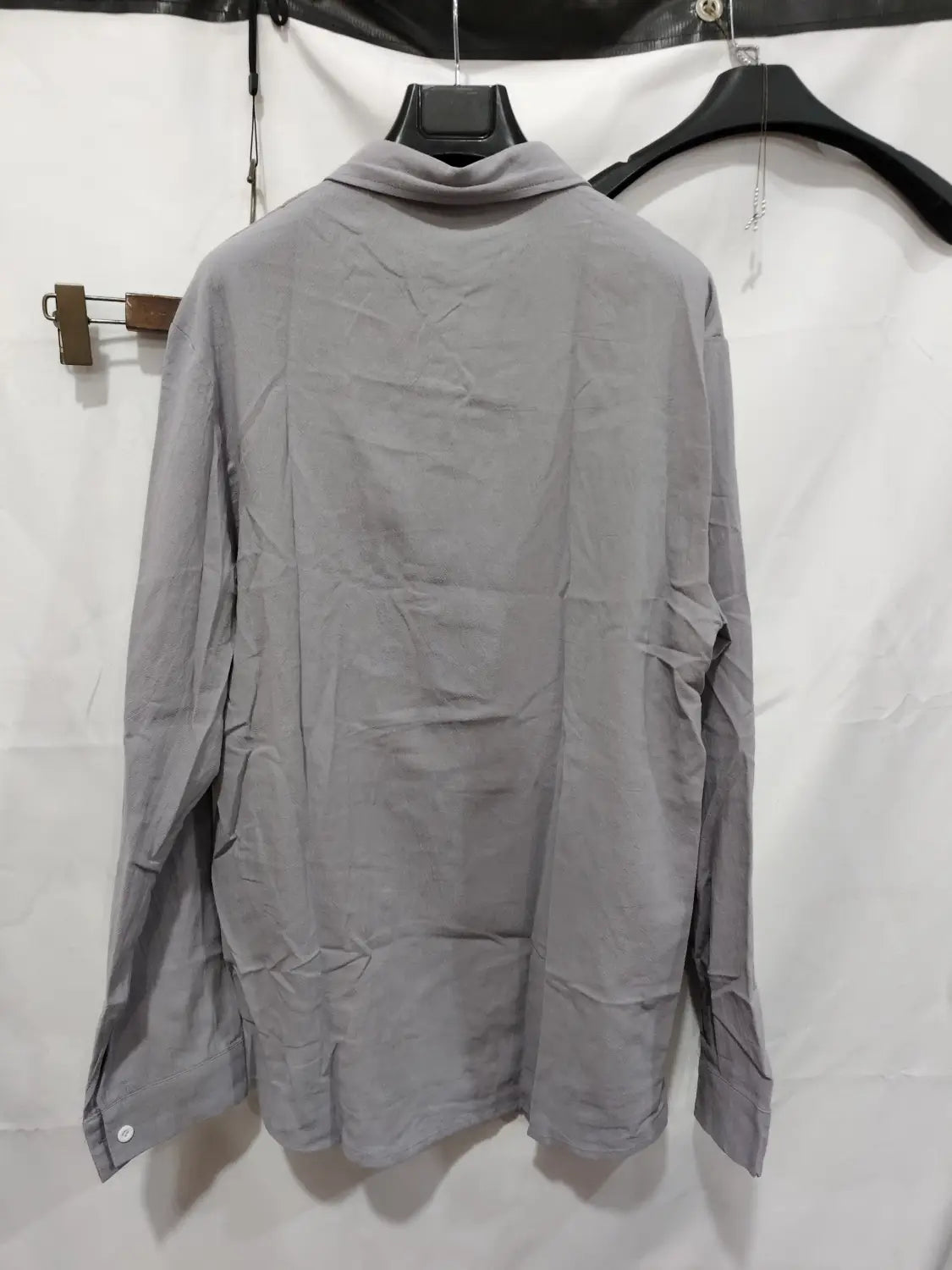 Chemise décontractée en coton et lin gris, à manches longues et col, suspendue à un cintre noir.
