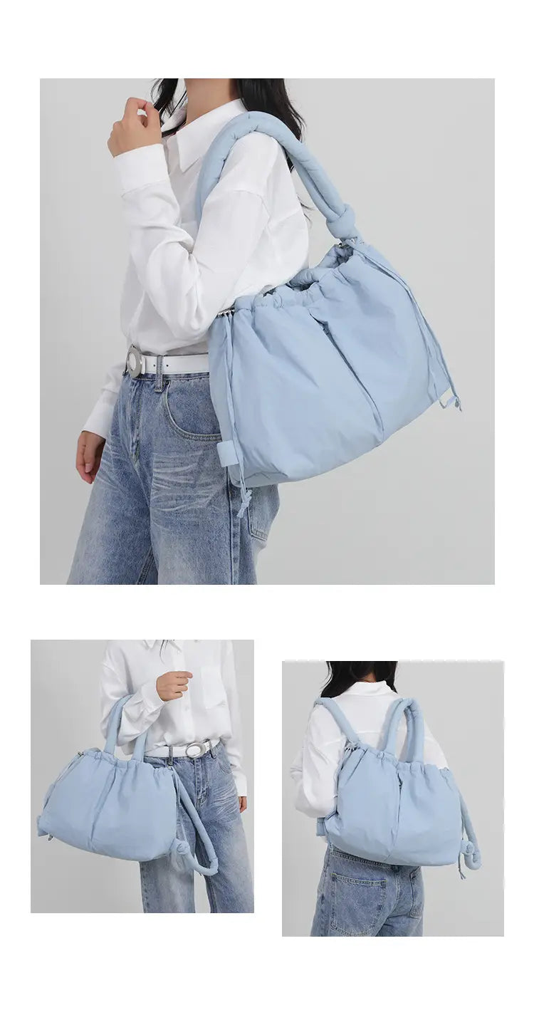 Light blue quilted puffer tote bag made of lightweight nylon with a canvas shoulder strap, drawstring closure, and tassel details.