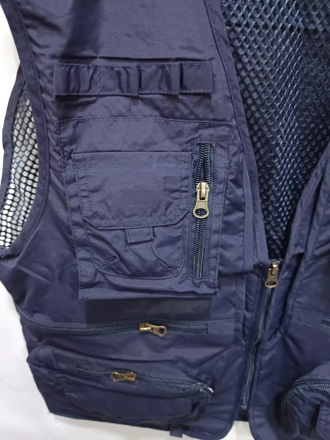 Dunkelblaue taktische Wanderweste mit Mesh-Rückseite, 14 verschließbaren Reißverschlusstaschen und Reißverschlüssen in Messingoptik, ausgelegt als Cargojacke.