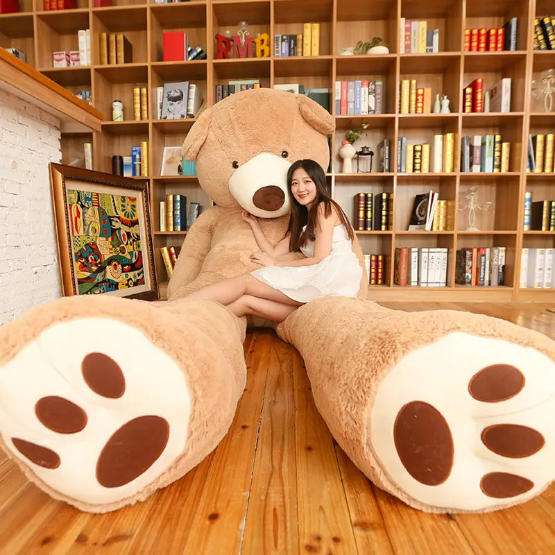 A plush tan-colored giant teddy bear plush toy with white paw pads and a brown nose featuring an unfilled leather shell.